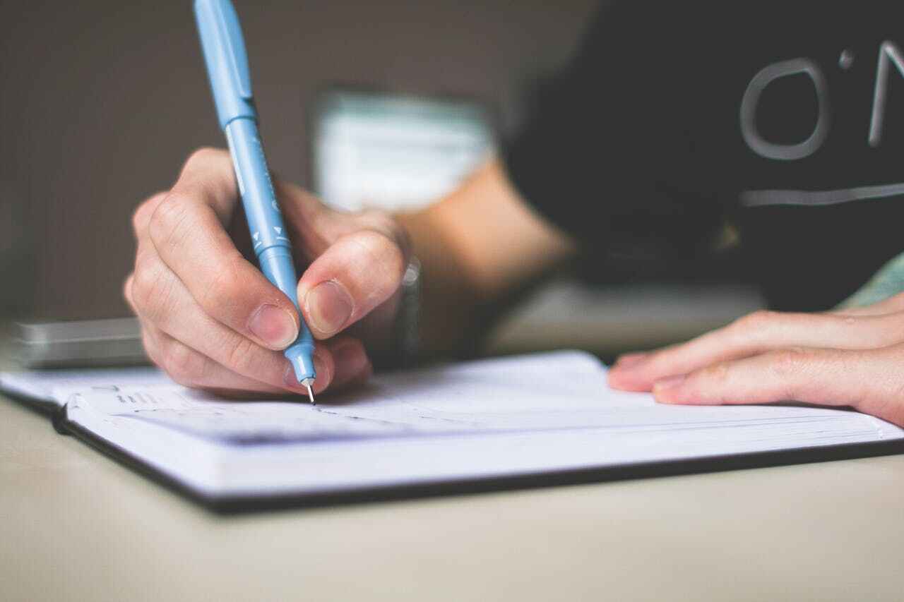 Seorang pelamar sedang menulis surat lamaran kerja bahasa inggris sebagai staff administrasi.